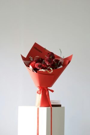 A beautiful red flower bouquet wrapped in stylish paper, perfect for special occasions.