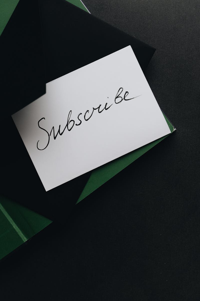 A minimalist image of a 'Subscribe' card in a green envelope on a dark background.
